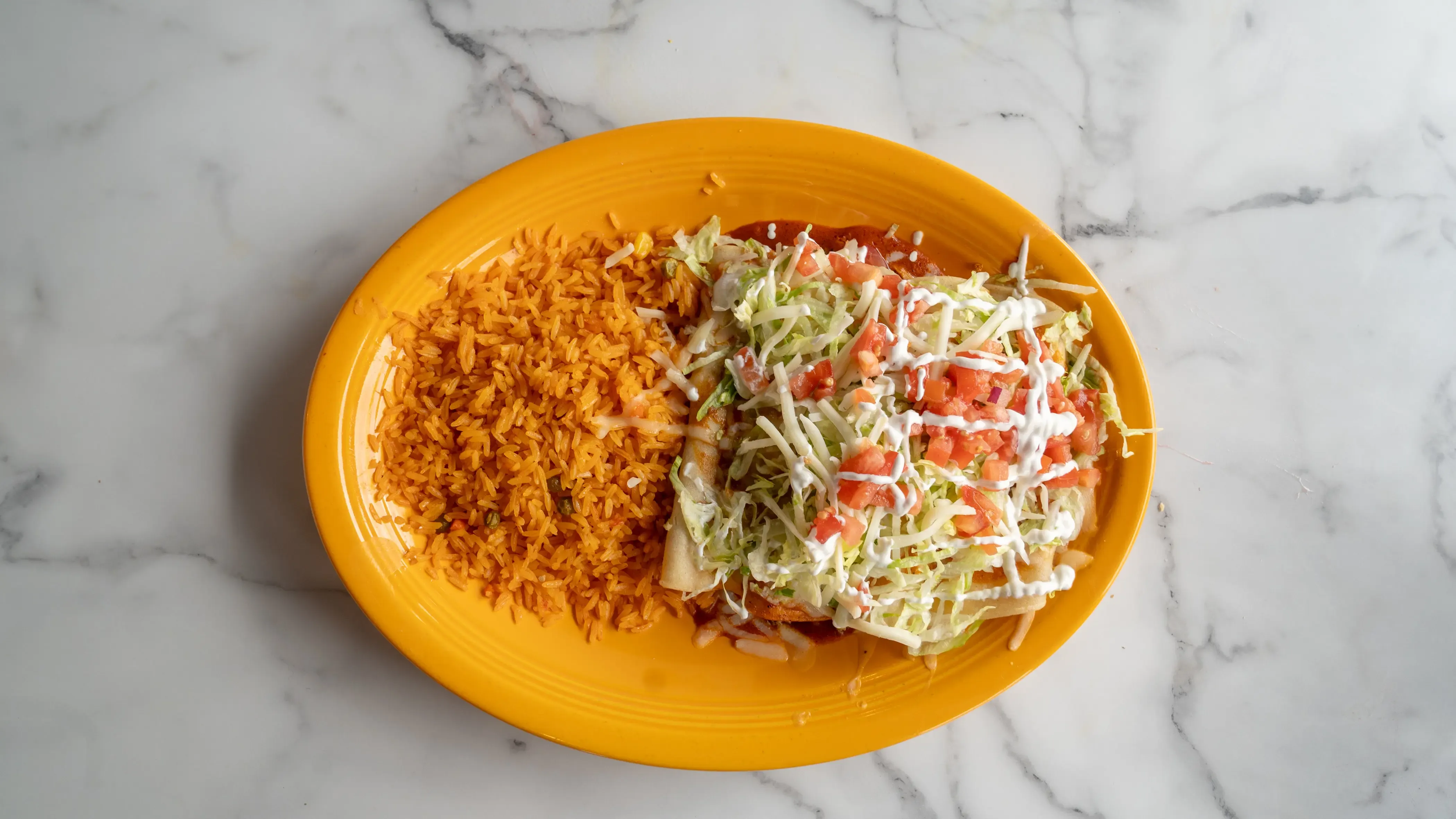 Four enchiladas showcasing our best: chicken, cheese, bean, and beef. Topped with your choice of mild red or green sauce, melted cheese, lettuce, tomato, and sour cream. Served with Mexican rice